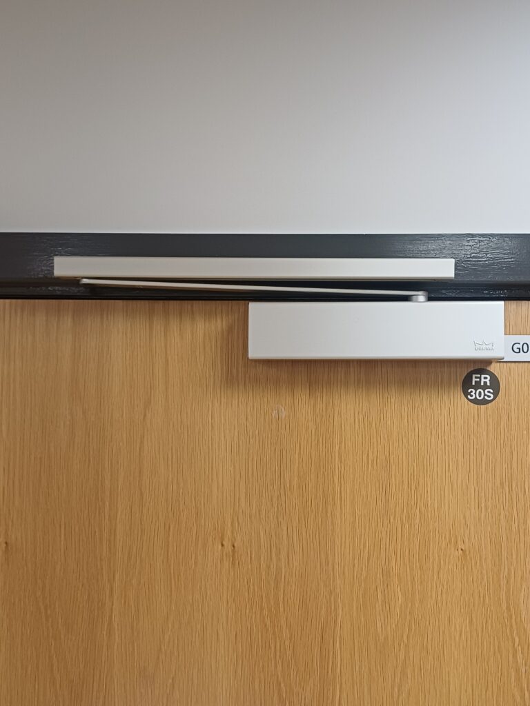 Fire door closer showing closer hardware for inspection and fault finding